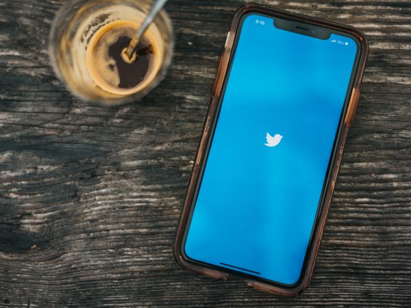 Twitter logo on smartphone next to cup of espresso