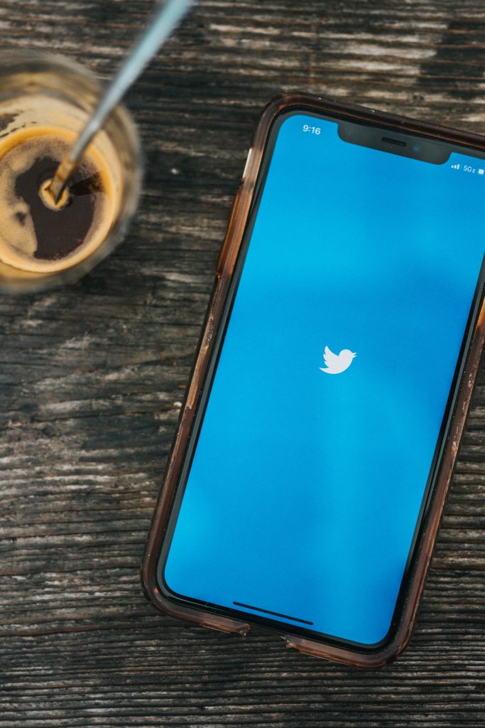 Twitter logo on smartphone next to cup of espresso