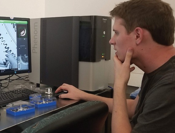 Male Microsystems Process Technician working at a computer station